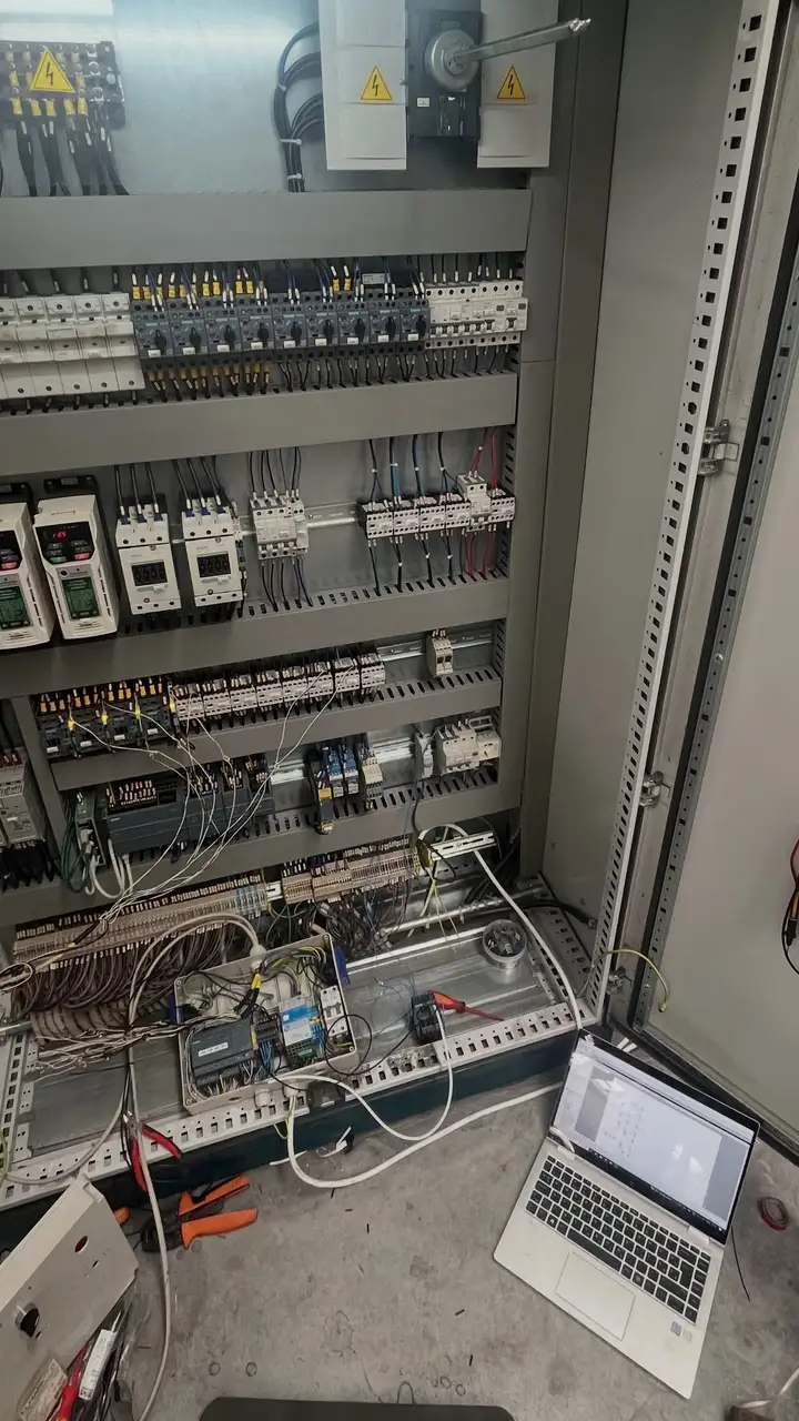 Otvoren elektro ormar s automatikom, na podu laptop i mjerni instrument